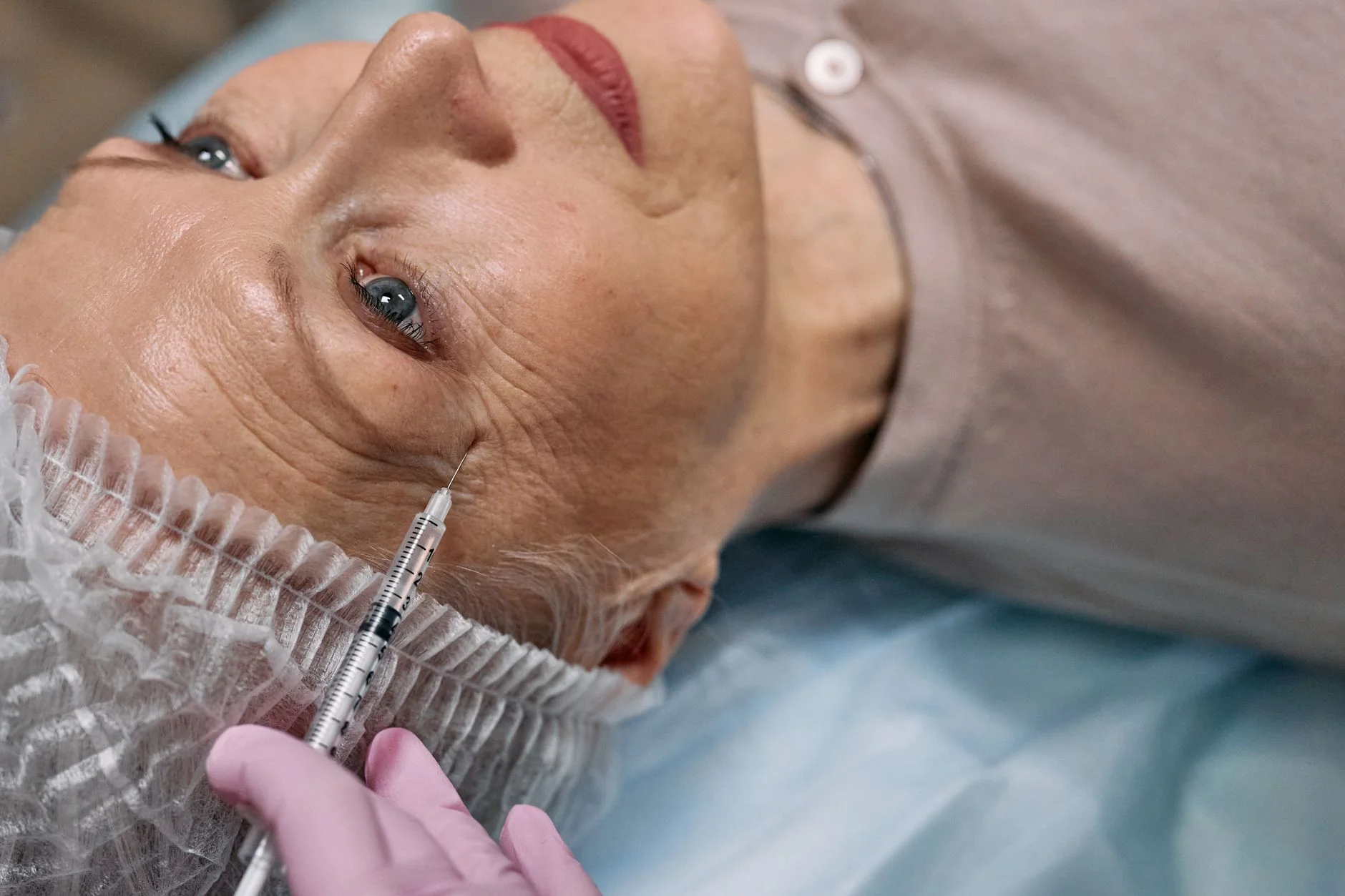 A senior woman undergoes a cosmetic injection procedure in a medical facility. at House of Aetheria, Gurugram