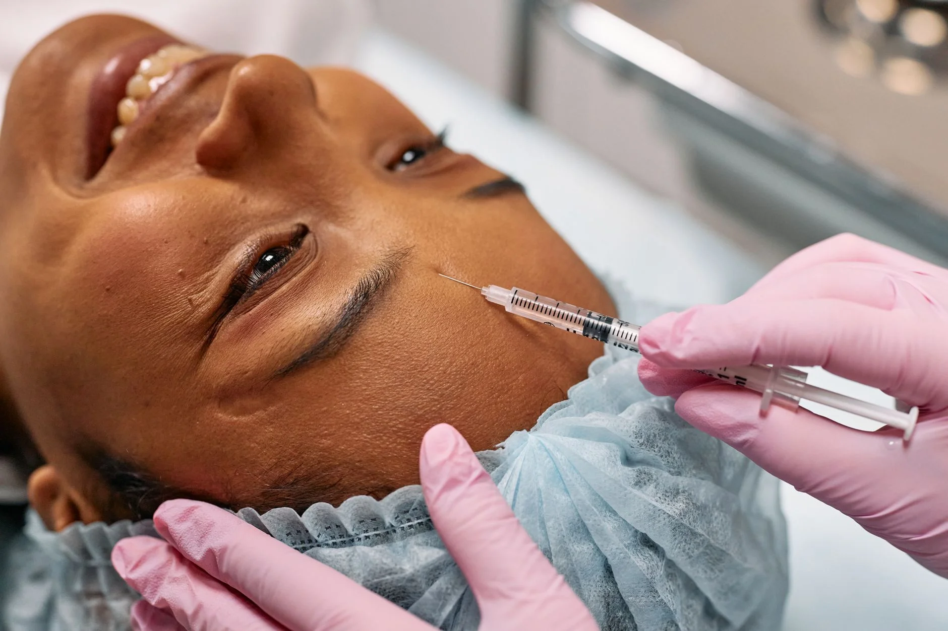 Close-up of a woman receiving a cosmetic injection on her forehead in a clinical setting. at House of Aetheria, Gurugram