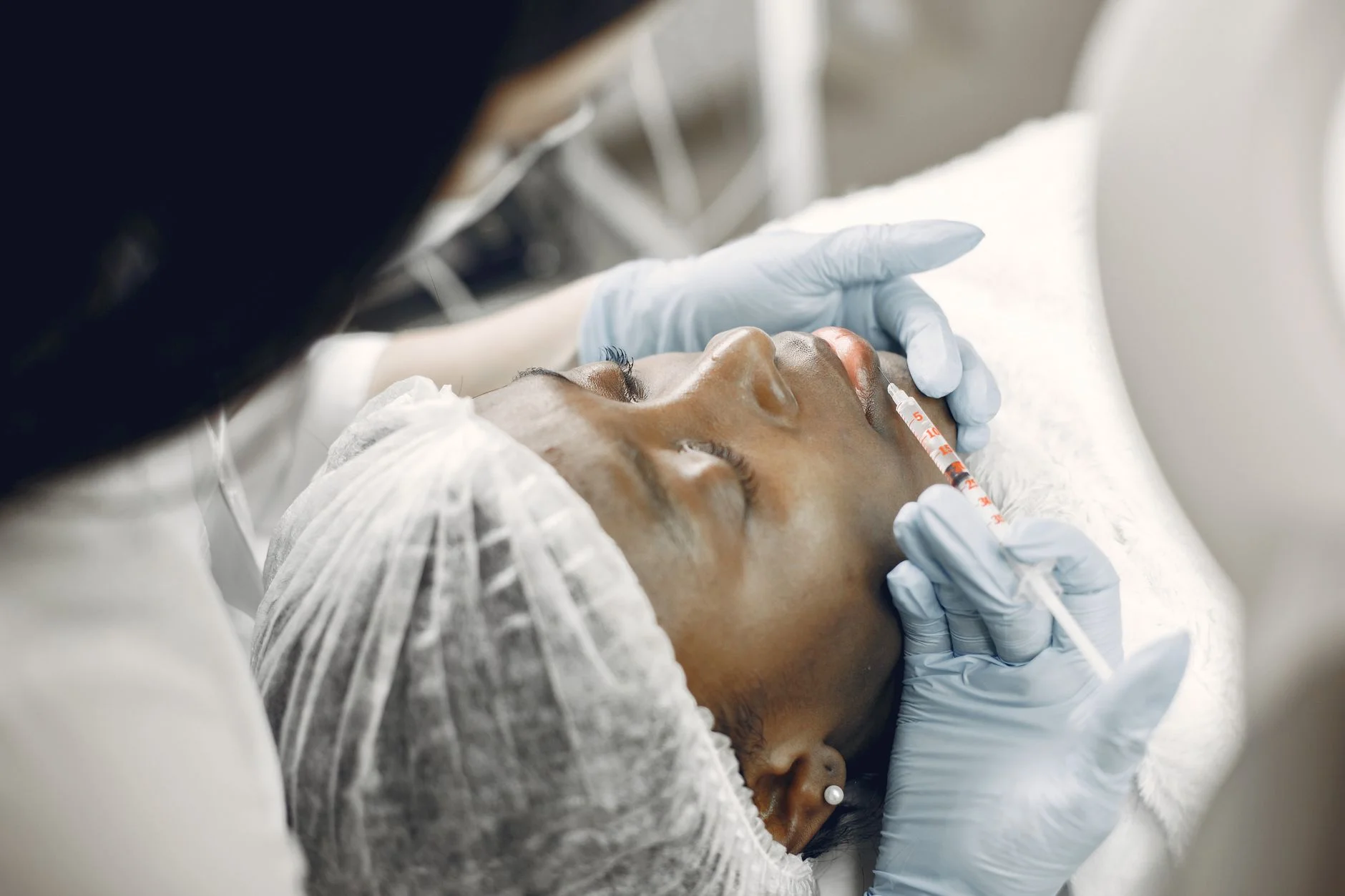 Close-up of a woman receiving a cosmetic lip injection in a clinic setting. at House of Aetheria, Gurugram