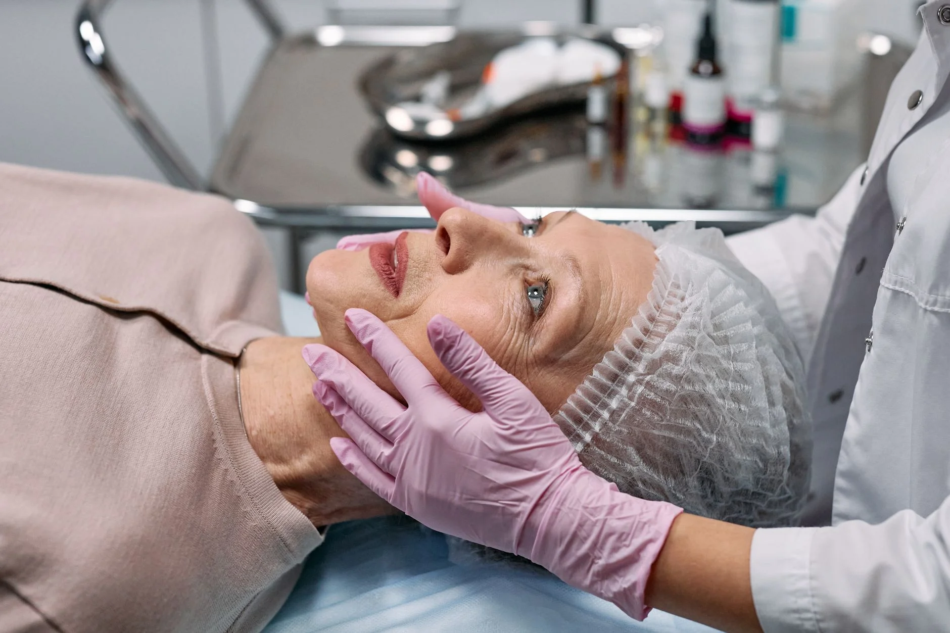Medical professional examining a senior woman's face in a clinical setting. at House of Aetheria, Gurugram