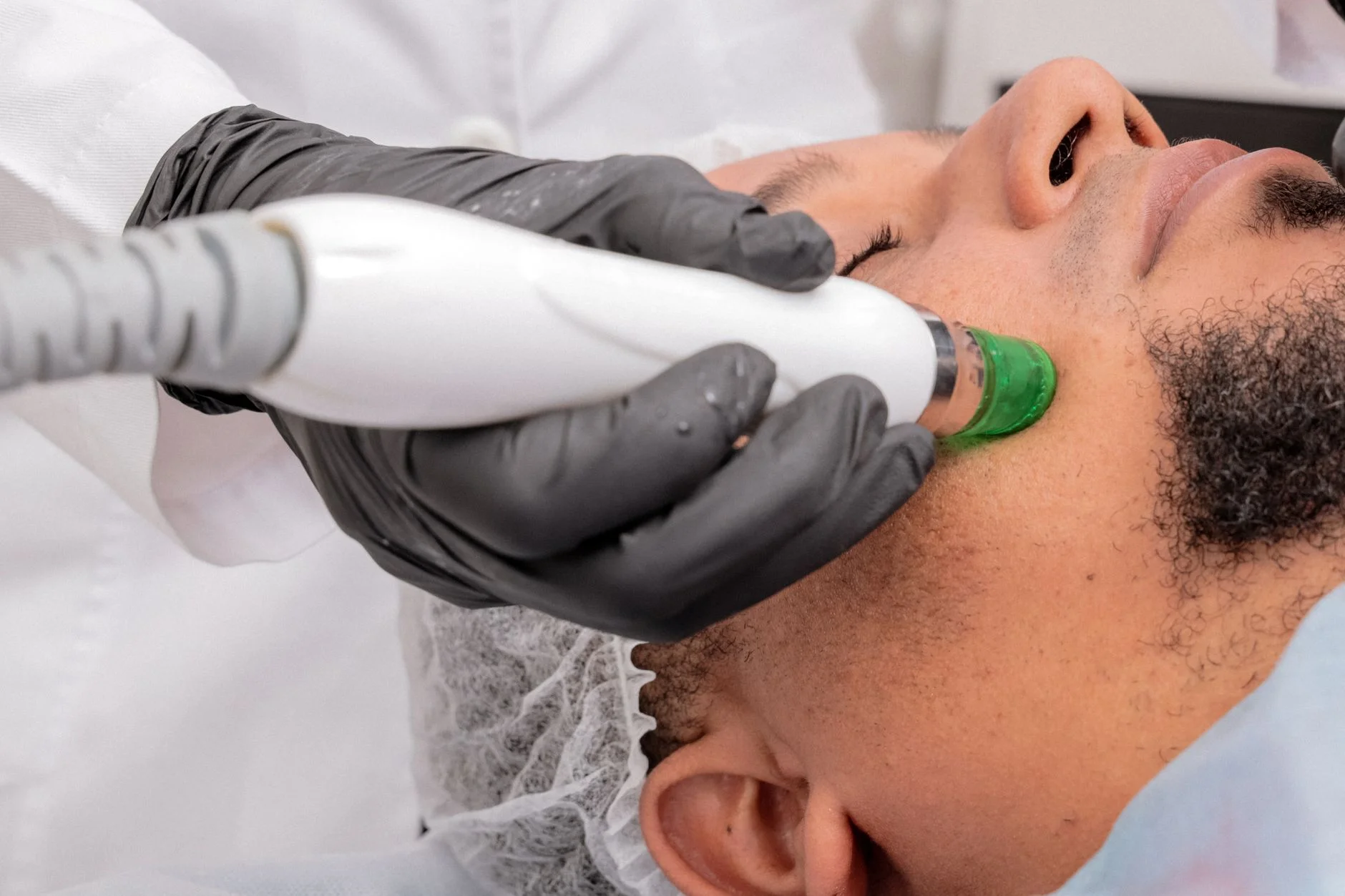 A close-up of a man receiving a professional skincare treatment in a clinical setting. at House of Aetheria, Gurugram