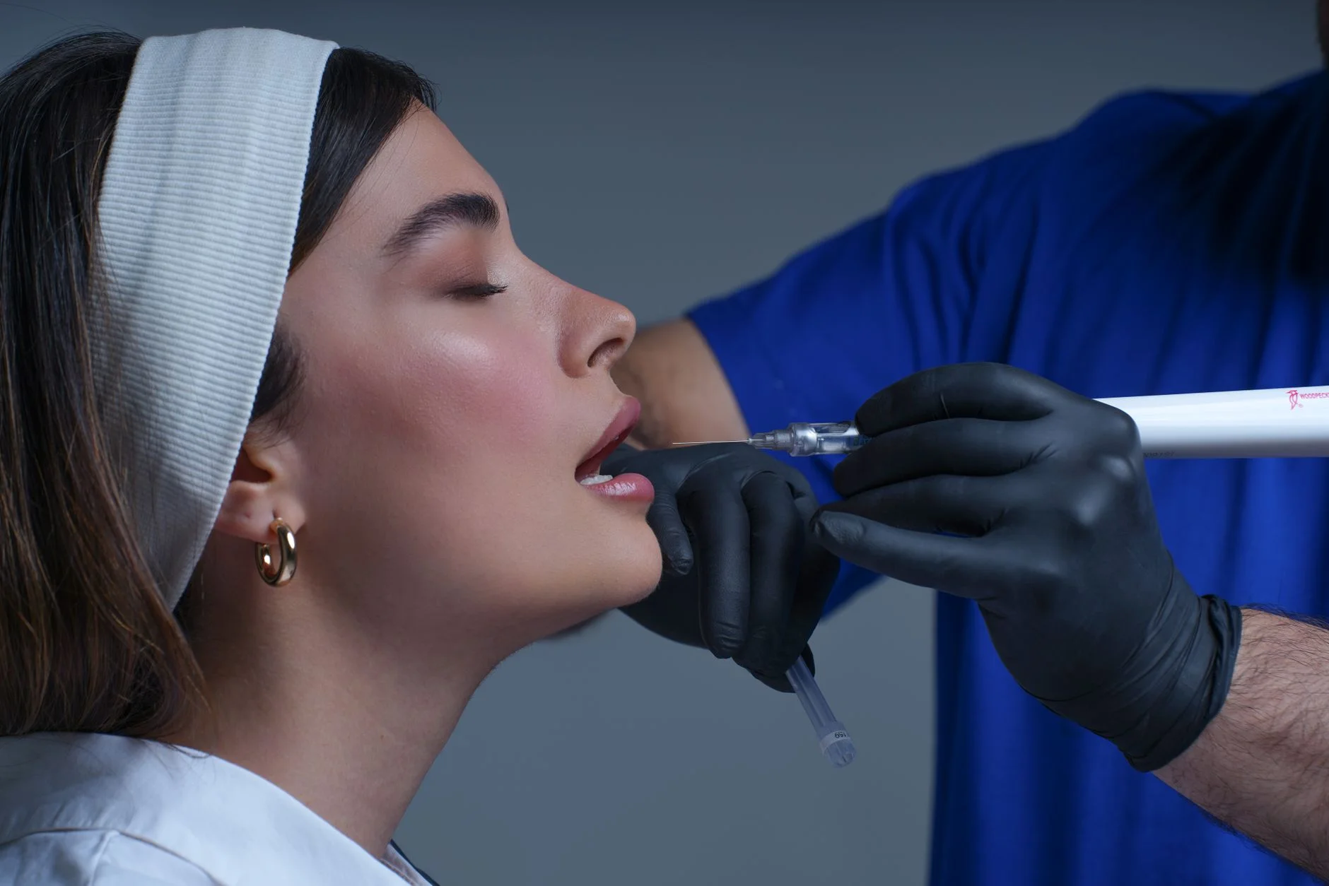 Close-up of a woman receiving a modern cosmetic treatment in a clinical setting. at House of Aetheria, Gurugram