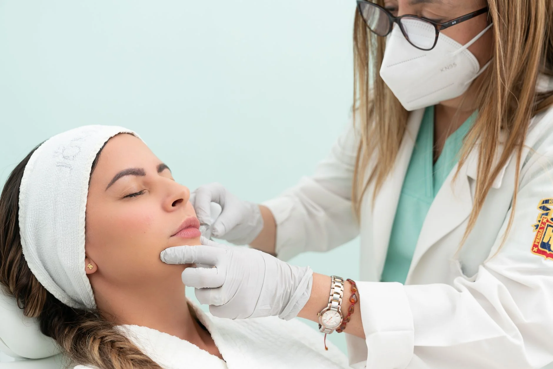 Doctor performing cosmetic treatment on a woman with eyes closed in a clinical setting. at House of Aetheria, Gurugram