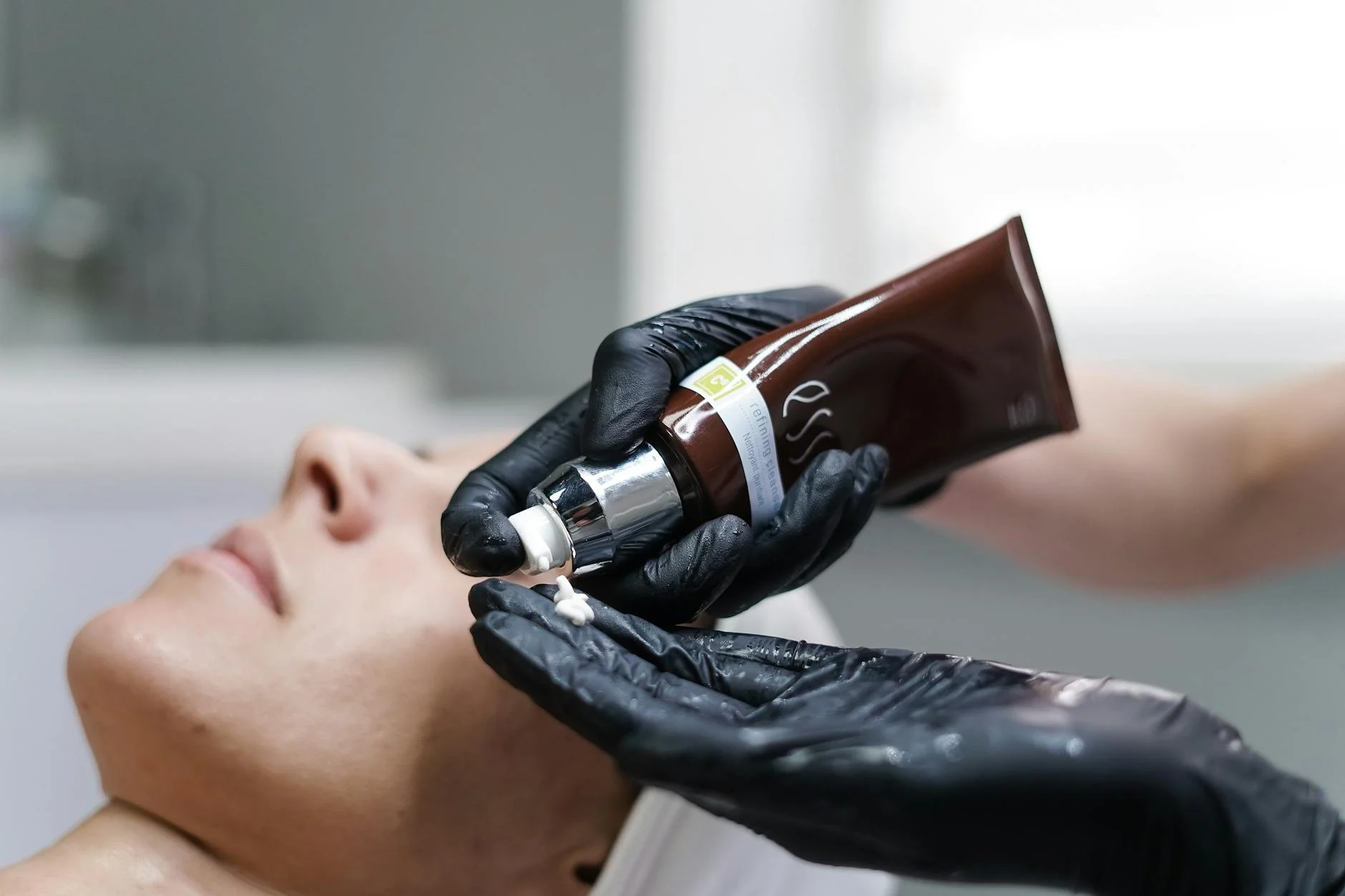 Close-up of a skincare professional applying cream with gloves during a facial treatment in a clinic. at House of Aetheria, Gurugram