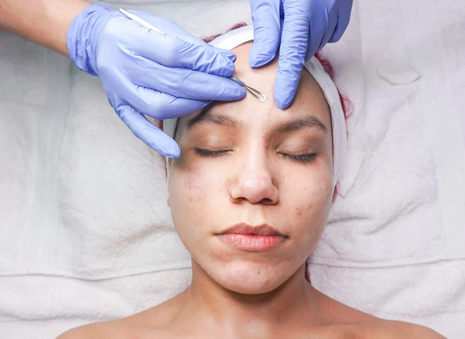 Woman undergoing professional facial treatment with eyes closed and gloves. at House of Aetheria, Gurugram