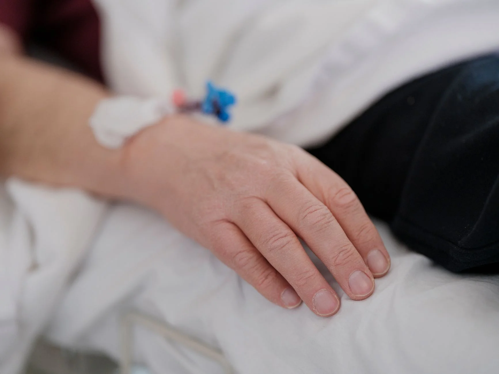 A close-up view of a patient's hand resting on a bed with an intravenous drip connected. at House of Aetheria, Gurugram